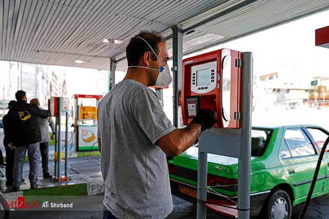 پمپ بنزین در ایران و شخصی که برای پرداخت وجه از ماسک و دستکش استفاده می کند.